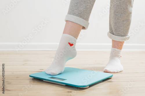 female legs on electronic scales on a wooden floor
