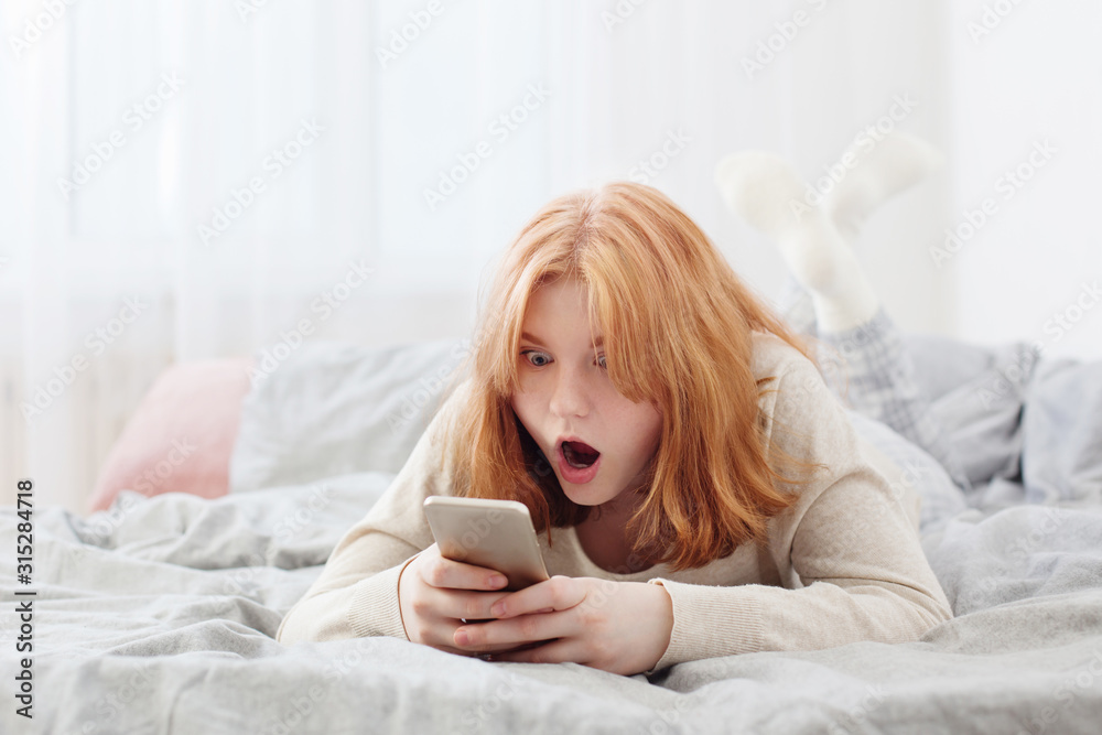 teenager girl with smartphone on bed