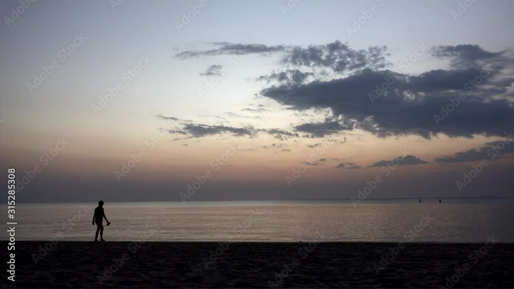 Silhouette of people walking Along the Beach at Sunset. Silhouette of people walking Along the Beach at Sunset.