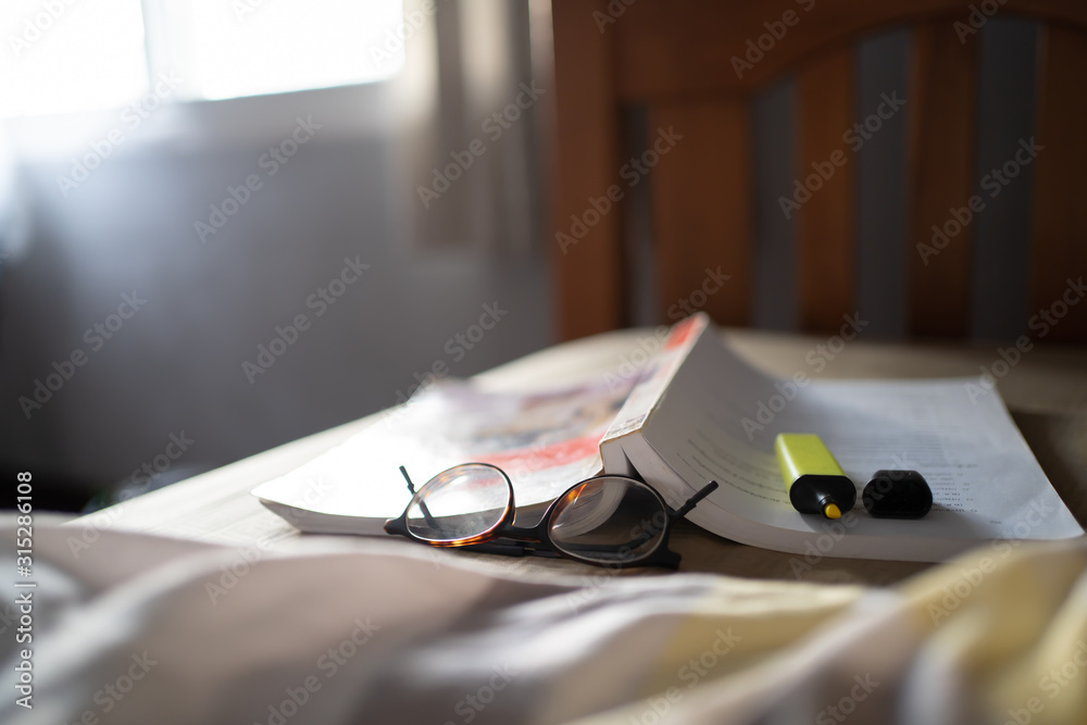 Textbook, Glasses and highlighter pen on the bed. - obrazy, fototapety, plakaty 