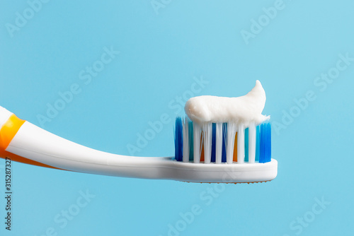 Toothbrush with white toothpaste close-up on blue background