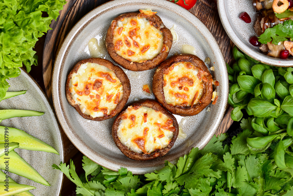 Georgian cuisine. Stuffed shampignon mushrooms with suluguni cheese baked in ketsi pan with greens and vegetables Georgian cuisine. Stuffed shampignon mushrooms with suluguni cheese baked in ketsi pan with greens and vegetables
