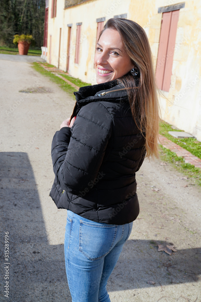 Young fashion slim woman blond in black jacket walking in city street rear behind view Young fashion slim woman blond in black jacket walking in city street rear behind view