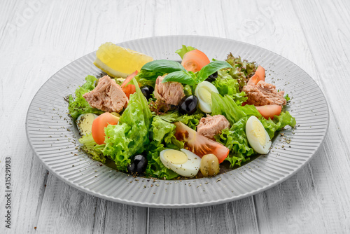 Tuna salad with tomatoes , olives , eggs and onion .
