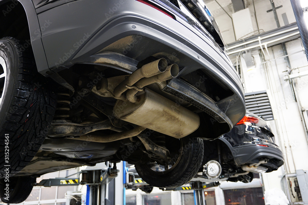 custom made wallpaper toronto digitalA modern car SUV in a service center is lifted on a lift for diagnosis, maintenance or repair. Close-up back of a car, muffler, bumper trim, exhaust pipe. Service station in the background is blurred.