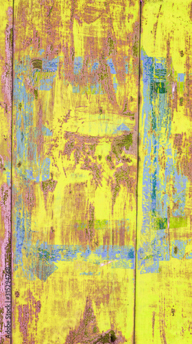 background of brightly painted metal garage wall in yellow, blue and pink colors with scratches and rust