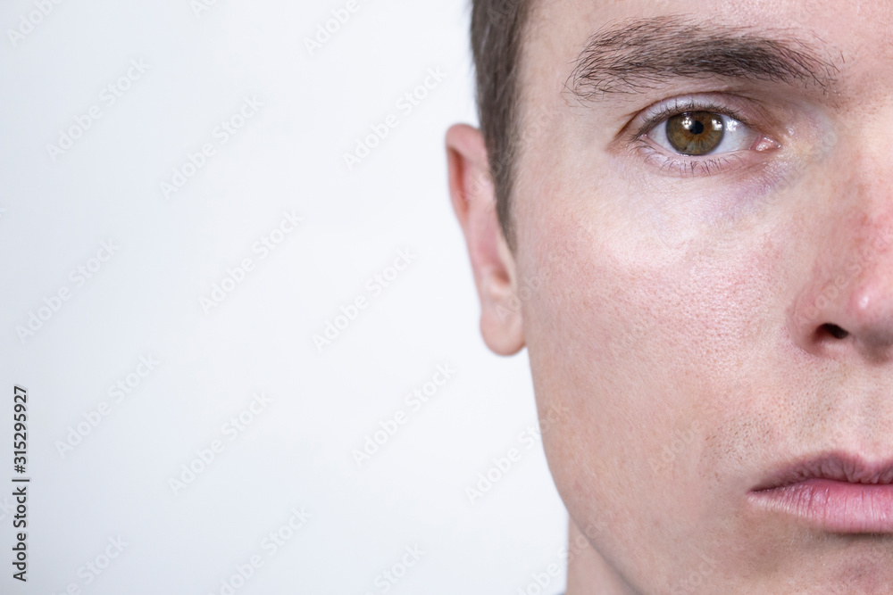 Fototapeta premium Half a man's face with the expression of grief on his face and tearful eyes.