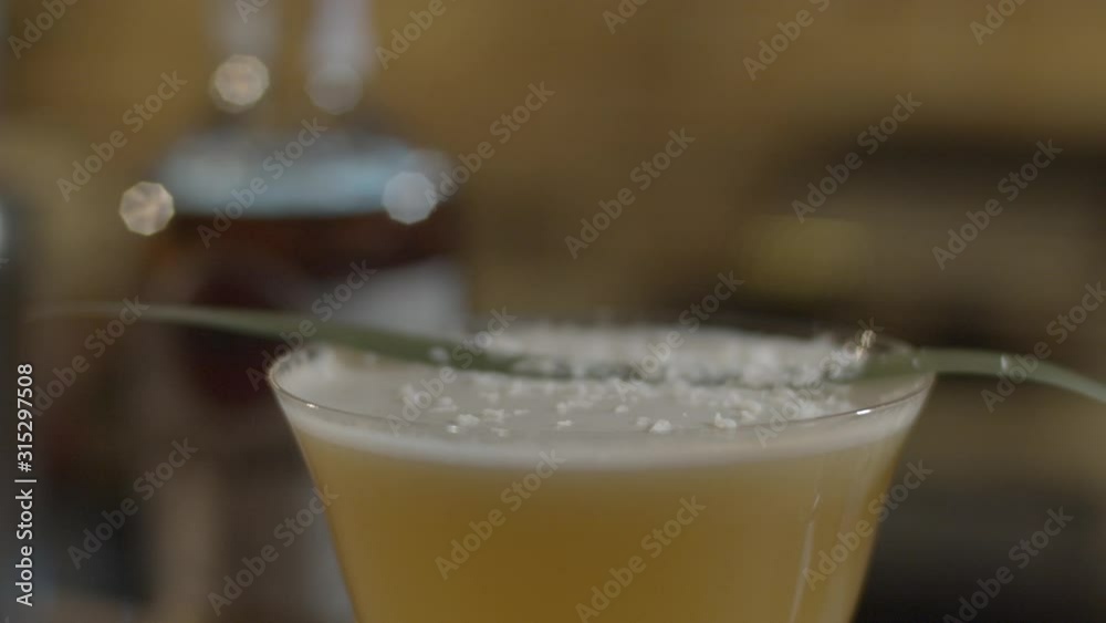 Barman in the white t-shirt mixing the yellow cocktail with foam on the bar table using shaker and sieve. Process of cocktail preparation Barman in the white t-shirt mixing the yellow cocktail with foam on the bar table using shaker and sieve. Process of cocktail preparation