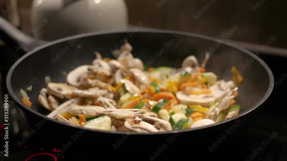 Female hand stirs vegetables fried in a pan. Female hand stirs vegetables fried in a pan.