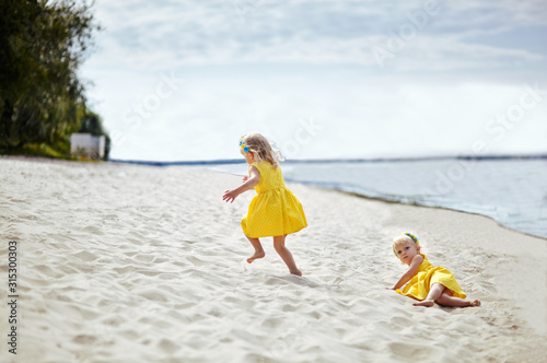 Adorable childs in dress posing outdoors. Little baby girls relaxing by the sea. Girls having fun together. Concept of summer,childhood and leisure