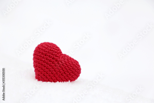 Valentine s day  red knitted heart in the snow. Background for romantic event  celebration or winter weather 