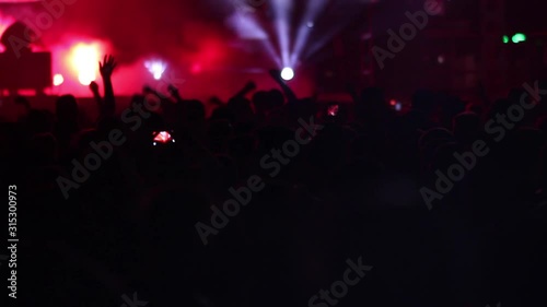 Colorful flash lights on smoke at concert stage in front of crowd applause and singing artist cheering, rock pop and rap music during show photo