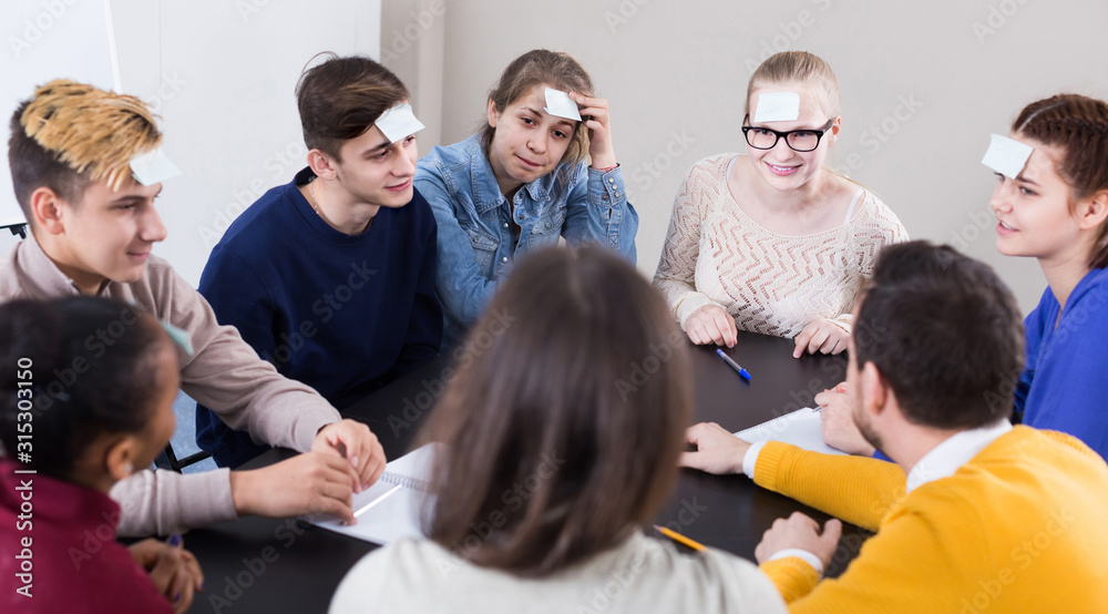 Fototapeta premium Classmates having round of guess-who game during class