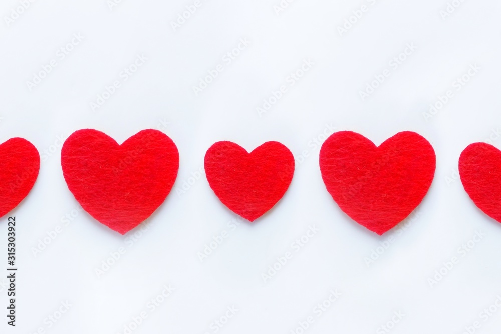 Red hearts in a row of felt on a white background. Valentine's day symbol, holiday concept, minimal style. Top view with copy space for text. Red hearts in a row of felt on a white background. Valentine's day symbol, holiday concept, minimal style. Top view with copy space for text.