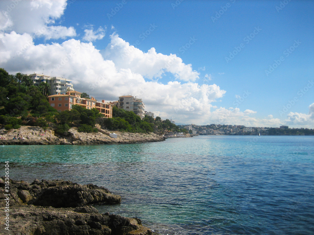Ausblick mediterran auf Bucht mit Meer in türkis blau, vor Himmel mit hellen Wolken, auf Hotel und Ferienwohnung und Küstenlinie im Hintergrund auf Mallorca, Paguera, Balearen, Sonne scheint, Urlaub  