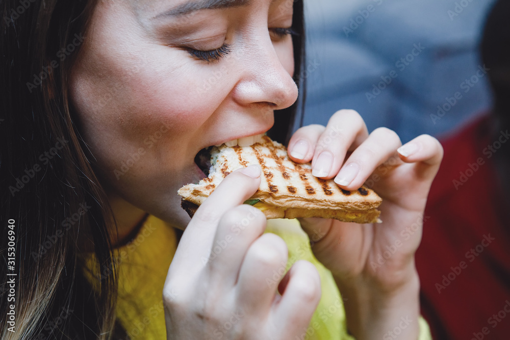 Woman eats a sandwich in a cafe. Woman eats a sandwich in a cafe.