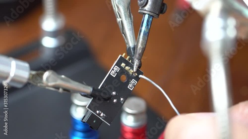 soldering the electronic circuit board footage, focused on soldering position, smake and melting lead is on the scene. photo