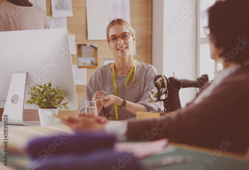 Female dressmaker is communicating with the potential client about custom-made dress in the sewing workshop photo