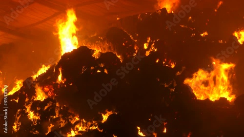 Bales of straw burning and smoking in a farm,  It will take several days for the fire to die out. Night.