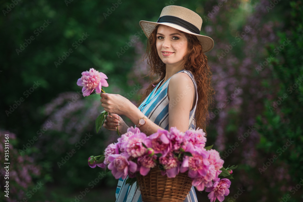A pretty woman in spring garden with pink peonies bouquet in the basket