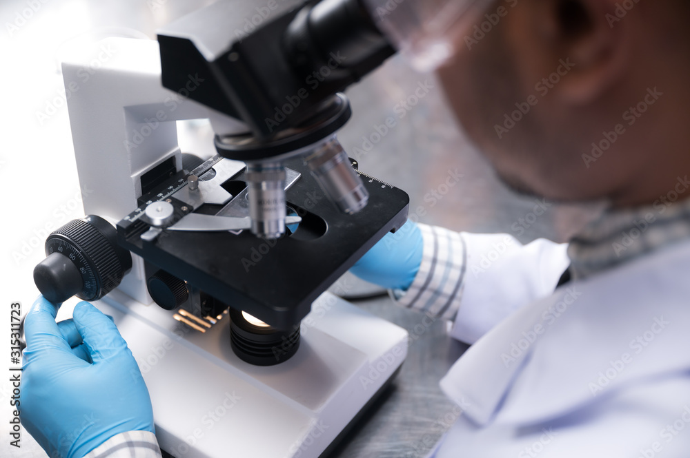 Young scientist working with a microscope in a laboratory. Young scientist doing some research. Young scientist working with a microscope in a laboratory. Young scientist doing some research.