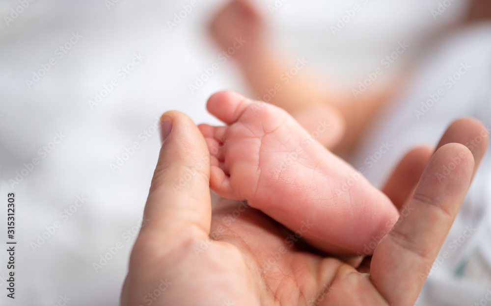 Mother hold in her hand her daughter feet