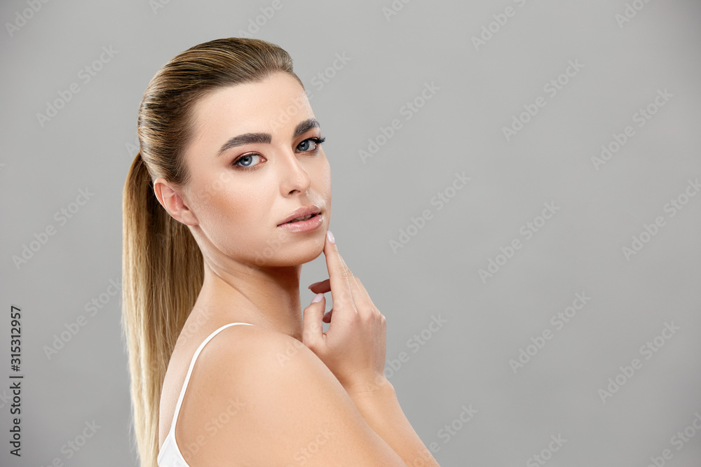 pretty woman with healthy skin and light make-up touching her chin and looking to camera pretty woman with healthy skin and light make-up touching her chin and looking to camera