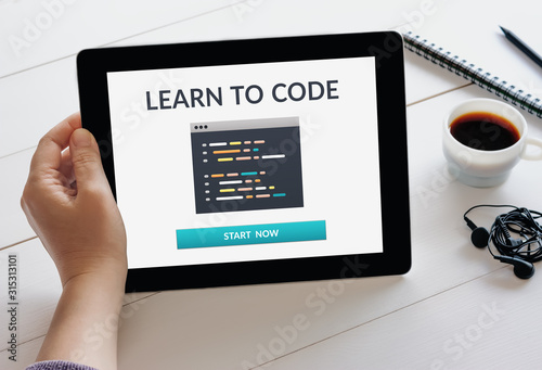 Hand holding tablet with learn to code concept on screen