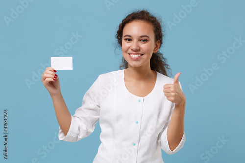 African american doctor woman isolated on blue background. Female doctor in white medical gown showing thumb up hold blank empty credit card. Healthcare personnel medicine concept. Mock up copy space. © ViDi Studio