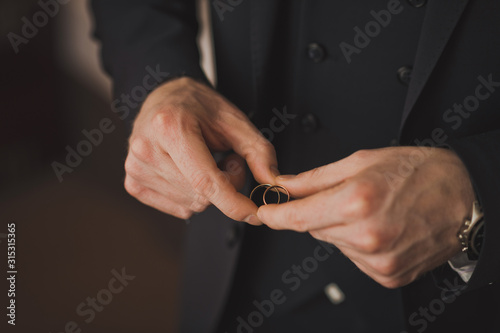 Mens hands leaning against each other wedding rings.