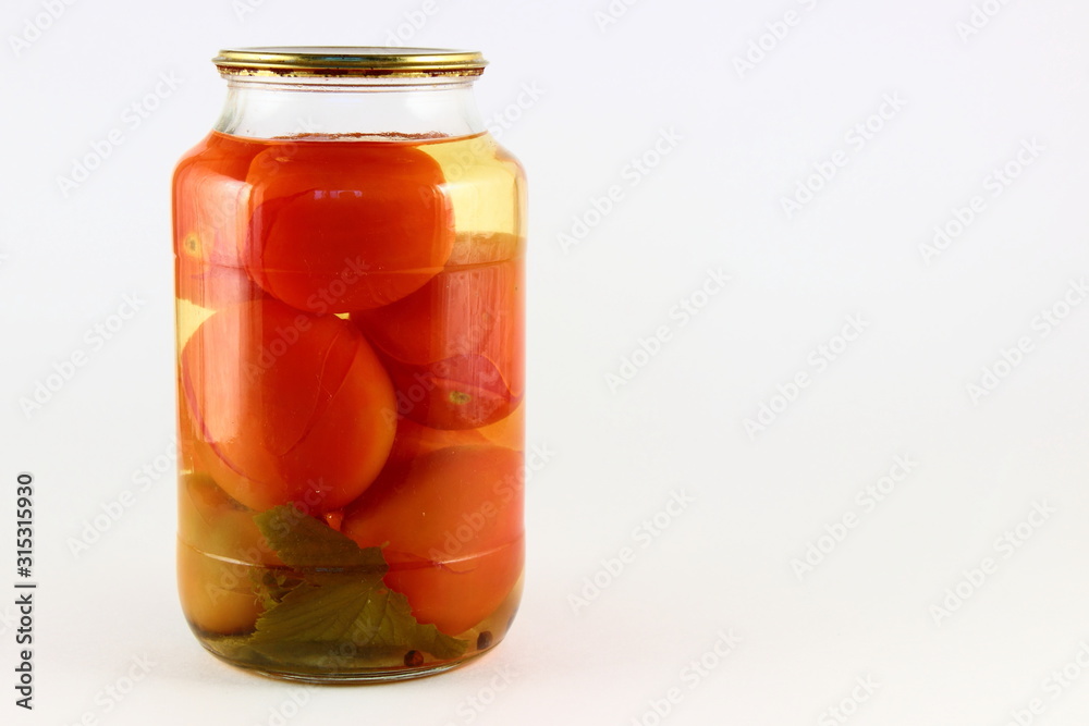 Juicy canned tomatoes in a glass jar with metal cap on white background with right copy space place, ecological homemade pickles Juicy canned tomatoes in a glass jar with metal cap on white background with right copy space place, ecological homemade pickles