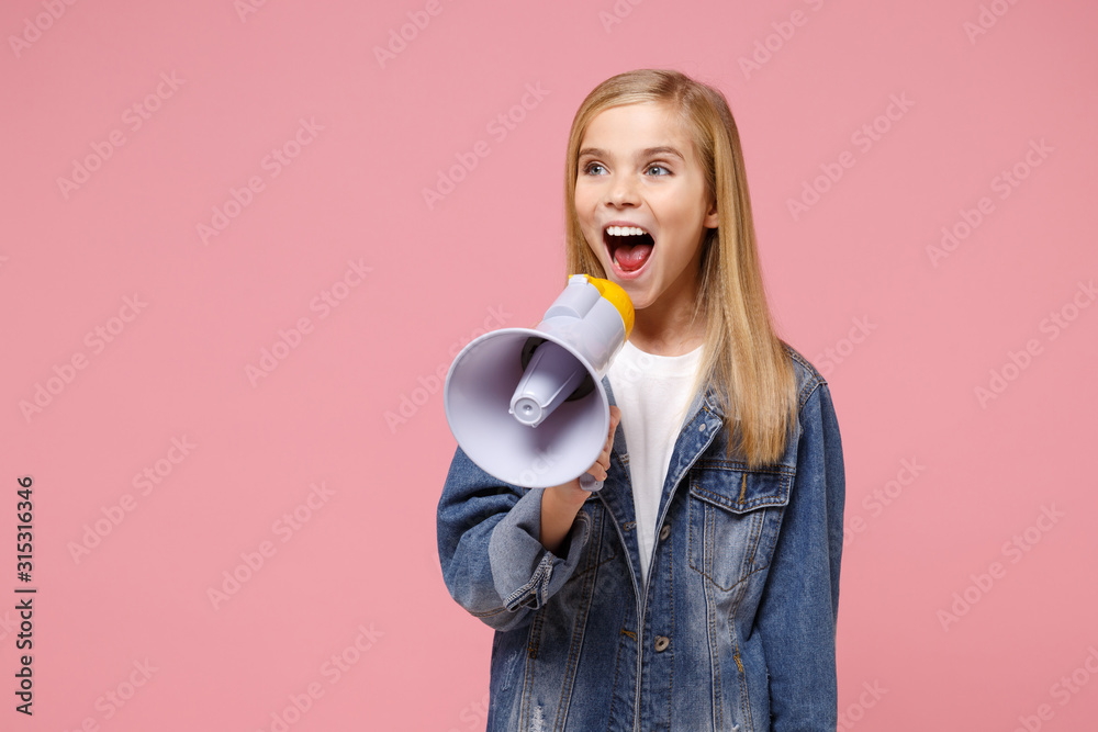 Pretty little blonde kid girl 12-13 years old in denim jacket posing isolated on pastel pink background children studio portrait. Childhood lifestyle concept. Mock up copy space. Scream in megaphone. Pretty little blonde kid girl 12-13 years old in denim jacket posing isolated on pastel pink background children studio portrait. Childhood lifestyle concept. Mock up copy space. Scream in megaphone.