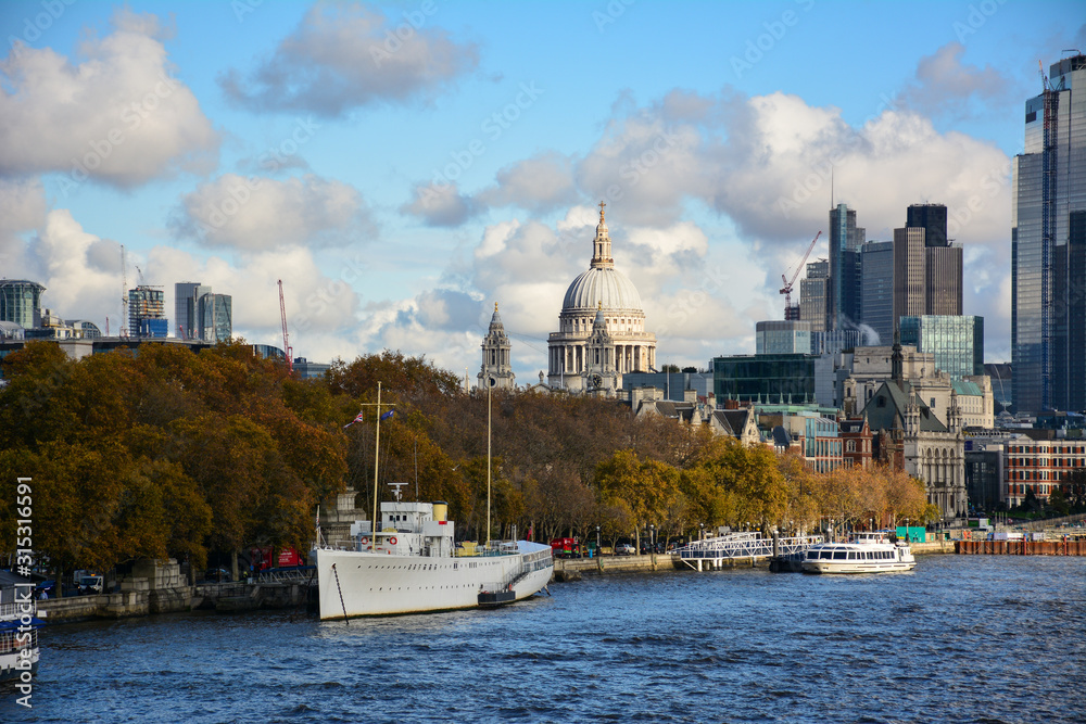 Panoramic view of London, UK, from Waterloo Bridge with the Thames, autumn trees on Victoria embankment, the dome of St Paul's Cathedral and the skyscrapers of City of London