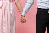 Cropped image of young couple two guy girl in party outfit celebrating posing isolated on pastel pink background in studio. Valentine's Day Women's Day birthday holiday concept. Holding hands folded.