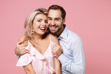 Smiling young couple two guy girl in party outfit celebrating posing isolated on pastel pink background in studio. People lifestyle Valentine's Day Women's Day birthday holiday party concept. Hugging.