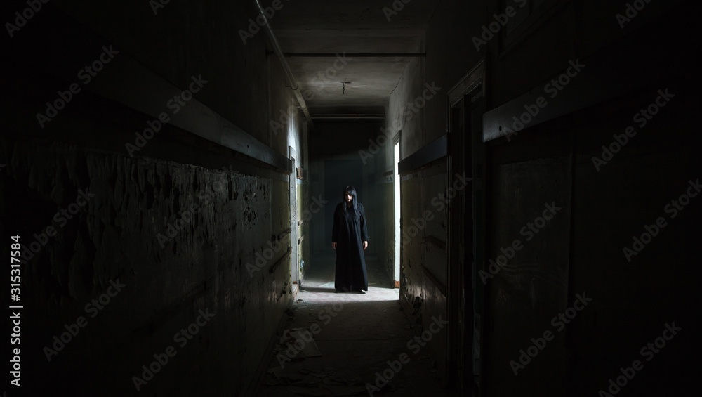 gothic brunette woman standing in long dark corridor