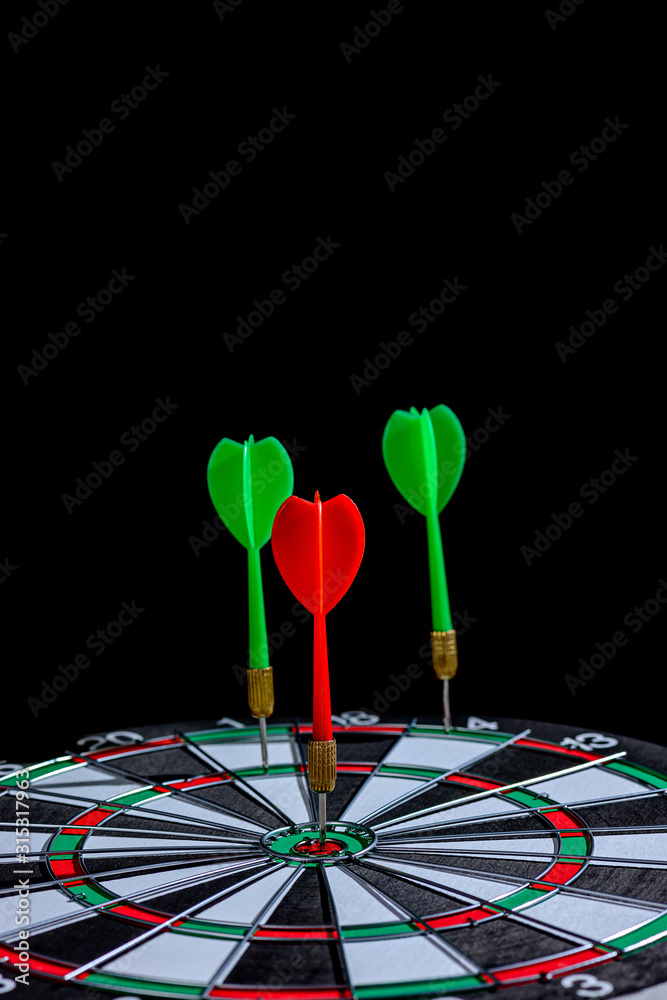 Fototapeta premium Red and green dart arrow hitting target center is Dart board Isolated on black background