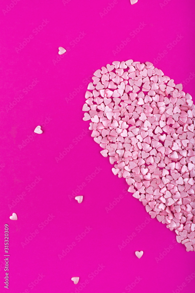Bright pink background. Pink half a heart on a pink background. Hearts sprinkles. Valentine day. Flat lay style. Top view. Sweet background. Confetti.