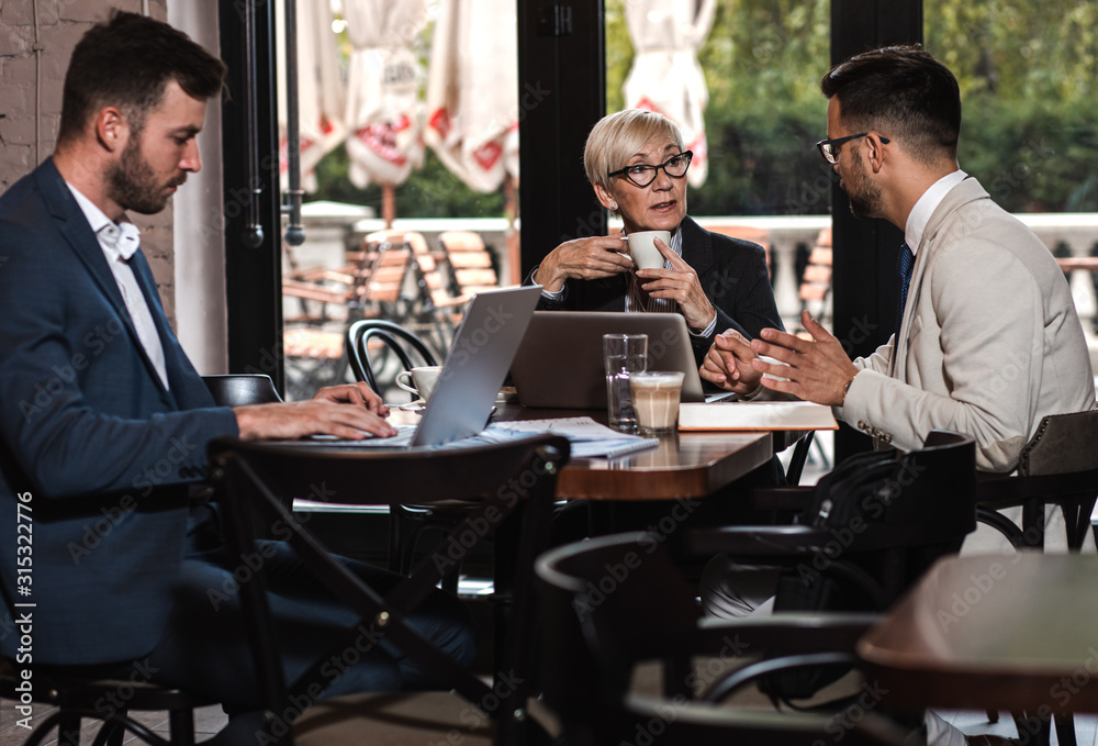 Senior businesswoman holding a meeting with her younger colleagues at office cafeteria. Senior businesswoman holding a meeting with her younger colleagues at office cafeteria.