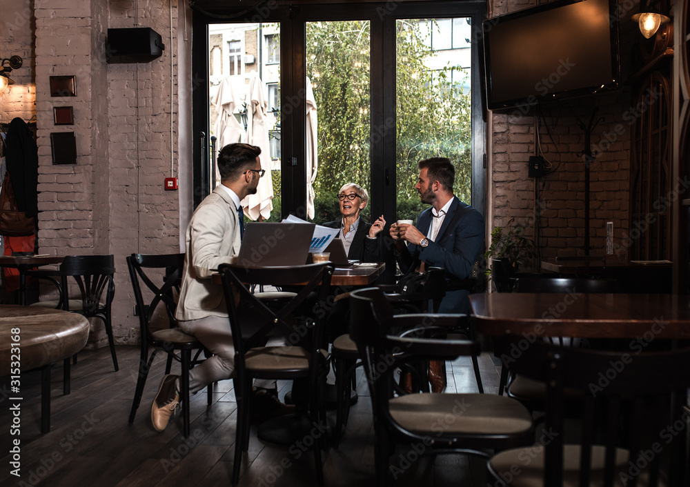 Senior businesswoman holding a meeting with her younger colleagues at office cafeteria.