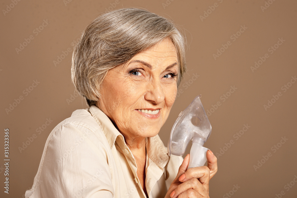 Portrait of elderly woman with flu inhalation on white background