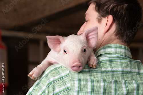 junger Landwirt mit kleinem Ferkel, süßes Schwein