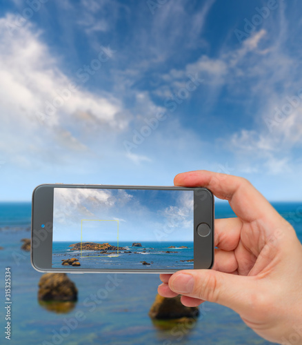 Large rocks in ocean near shore. Photo smartphone. Smartphone in hand. Landscape on monitor.