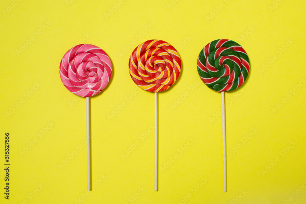 three colorful lollipop on yellow background three colorful lollipop on yellow background