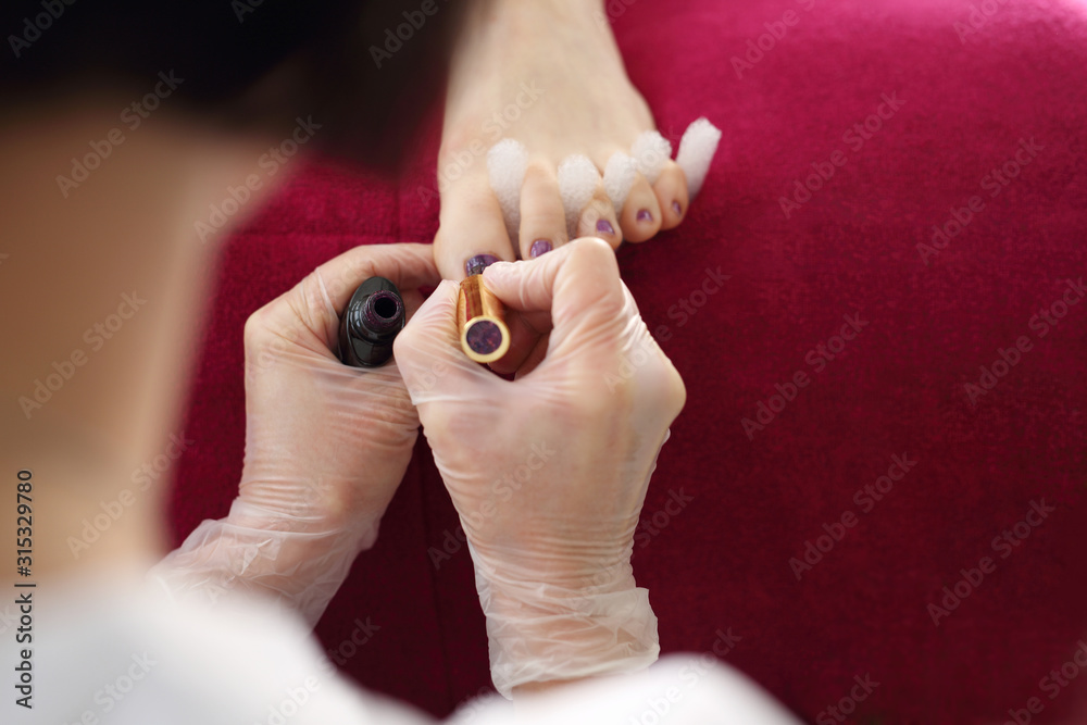 Naklejka premium Colorful pedicure, beautician paints the toenails.