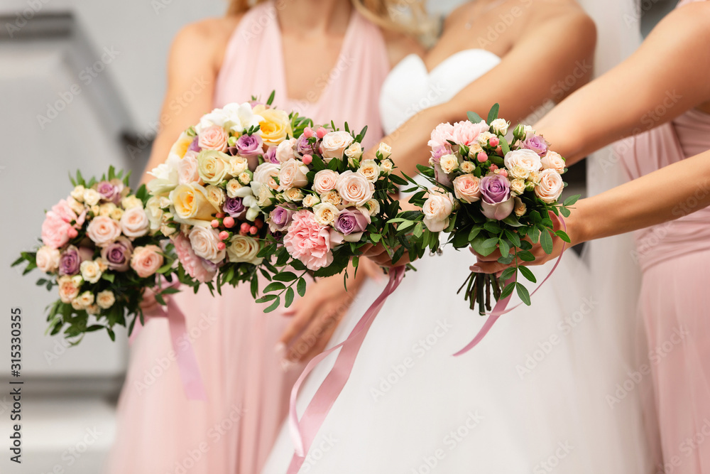 Bride and bridesmaids in pink dresses posing with bouquets at wedding day. Happy marriage and wedding party concept