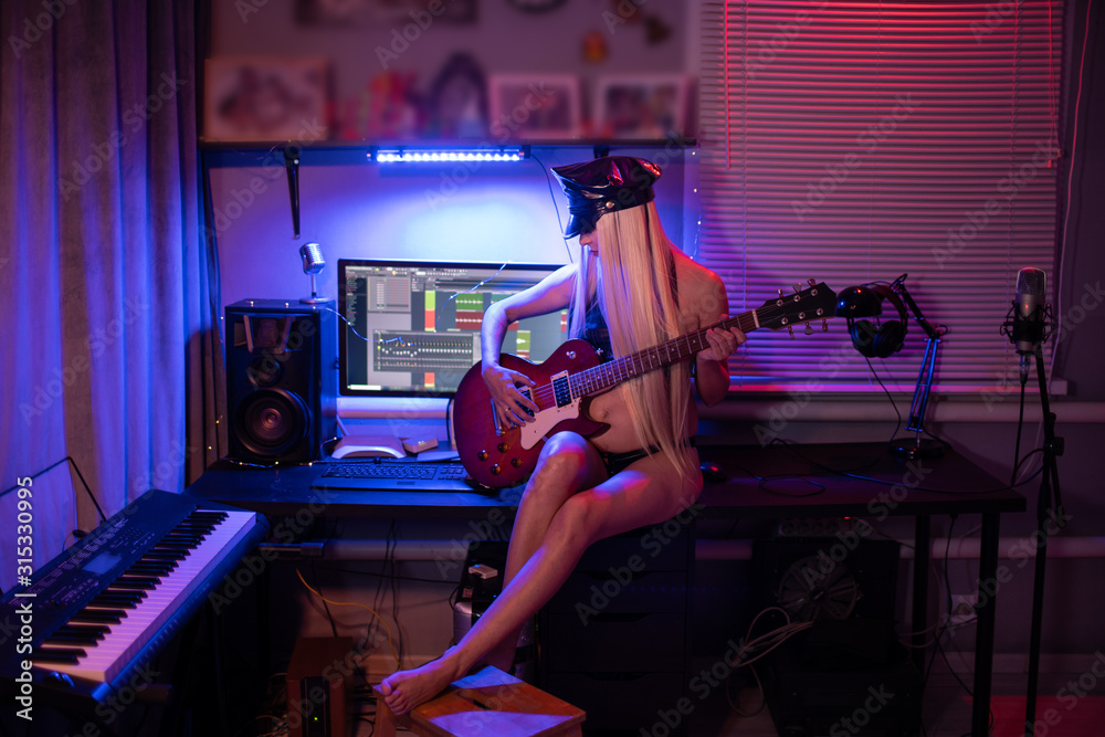 Fototapeta Woman Playing Guitar In Neon Light Blue And Red In Leather Clothes