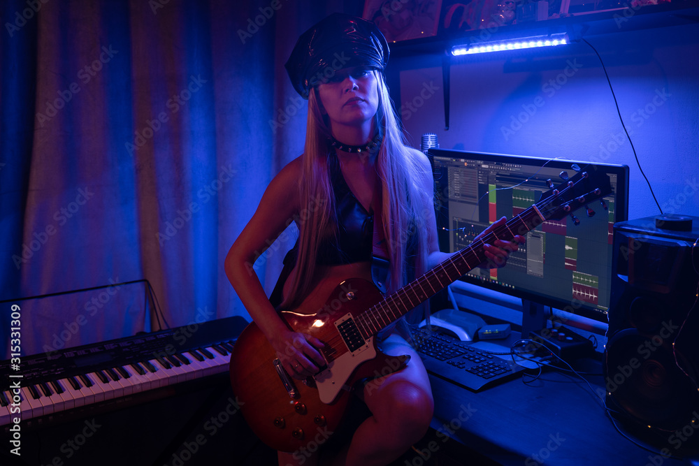Fototapeta Woman Playing Guitar In Neon Light Blue And Red In Leather Clothes