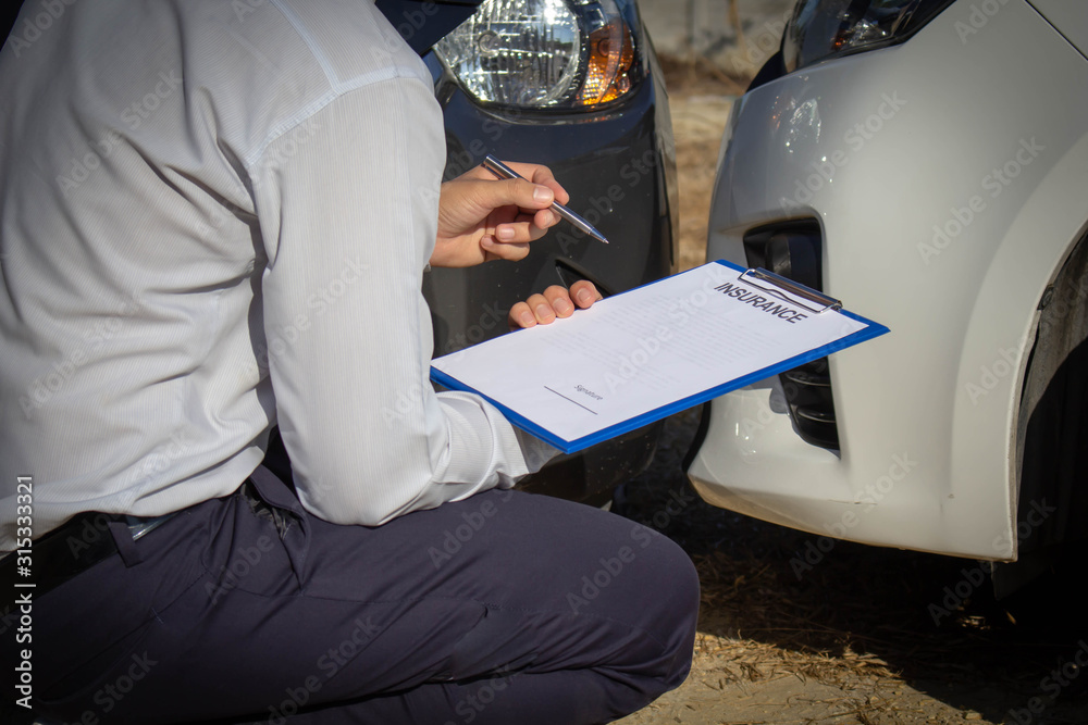 Car insurance agents check for damage from a car crash and fill out the ...