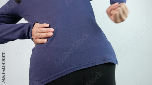 Close up of woman smash at the waist and her back by fist, suffering from backache at home. Health care and medical concept.